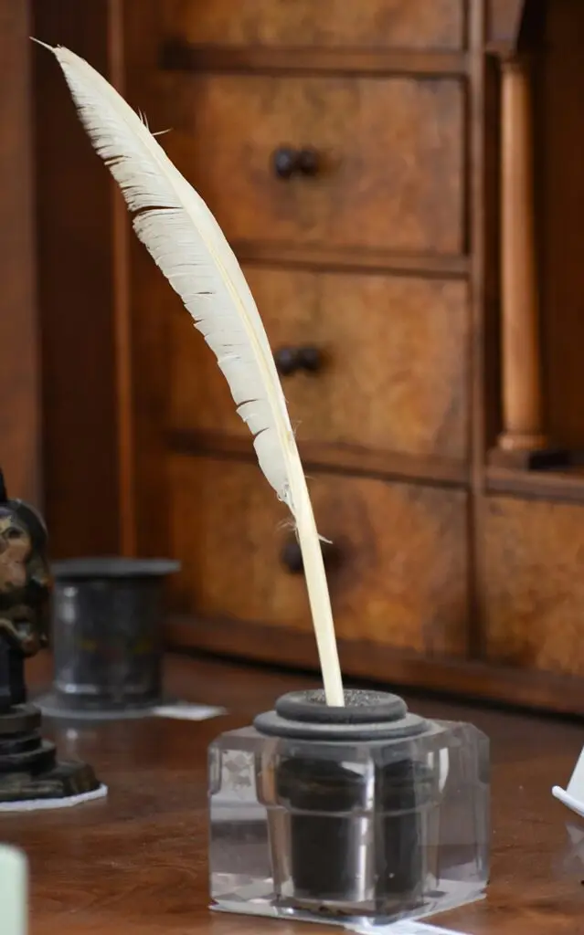 a quill and inkwell on a vintage desk