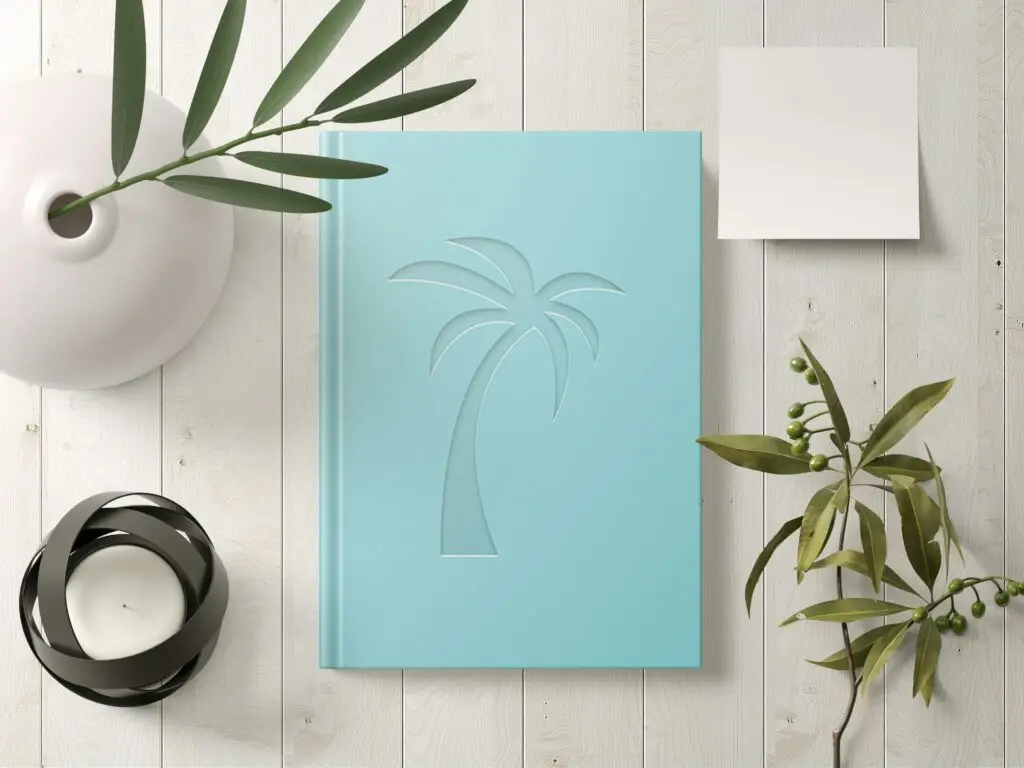 A birds eye view of a blue journal on a desktop with a candle and plants
