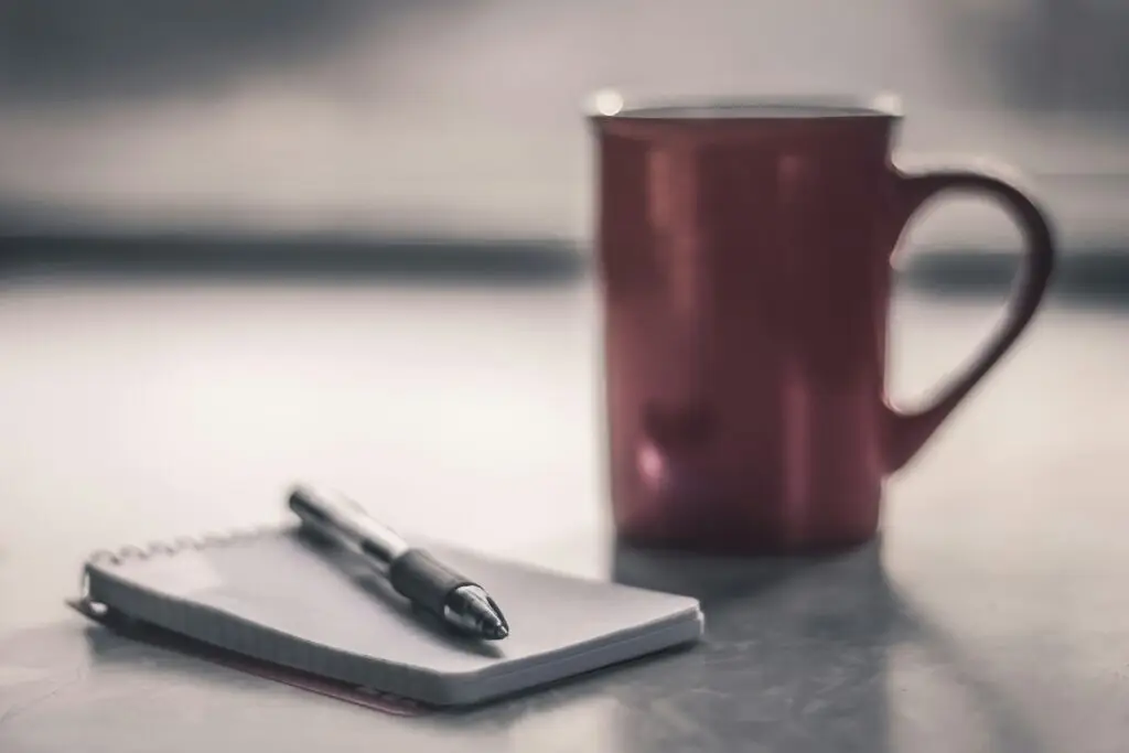 a notebook, pen, and coffee mug
